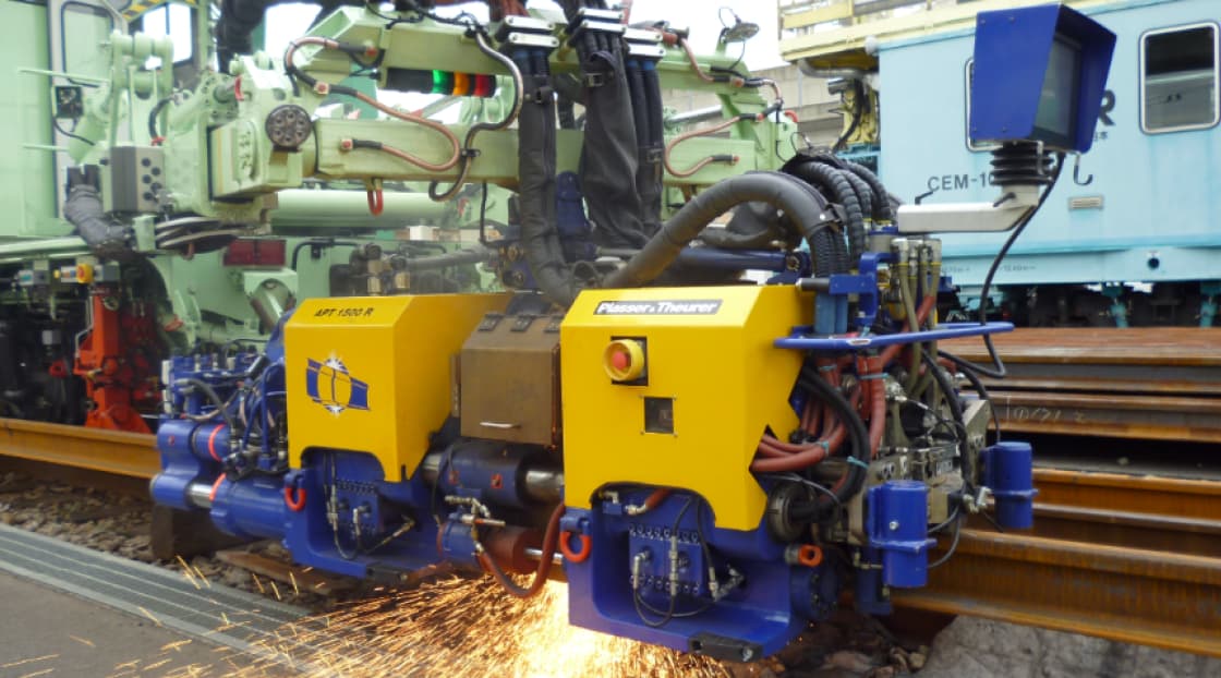 機械が火花を散らせながらレールの溶接作業をしている様子