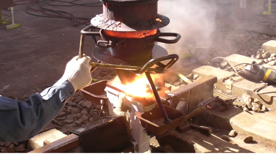 作業員が手持ちの溶接機を使ってレールの溶接を行なっている様子